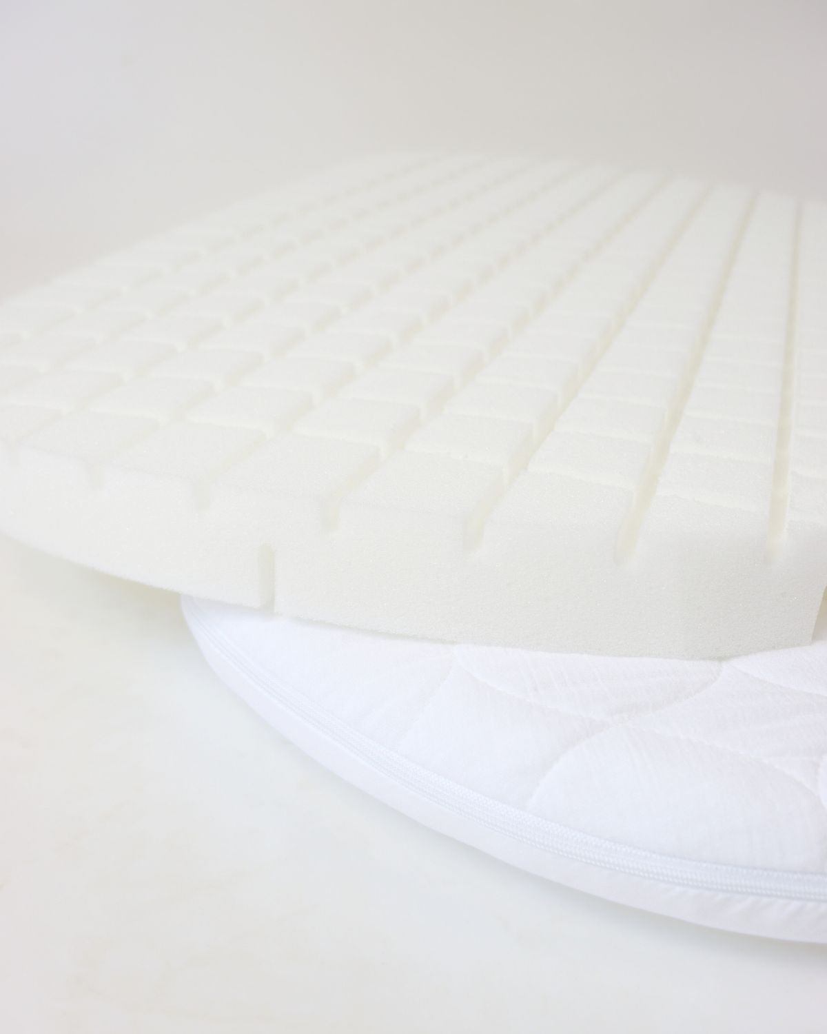 White foam core mattress with grid texture on top, fitted inside a quilted Stubenwagen mattress cover. - Mionido - Baby-Schumkernmatratzemit Musselinbezug